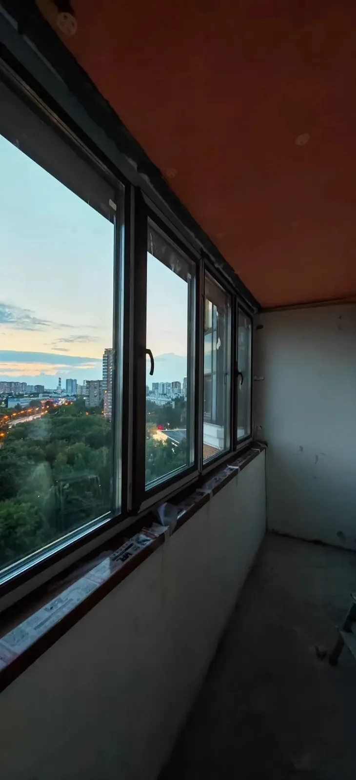 Остеклённая городская лоджия вечером